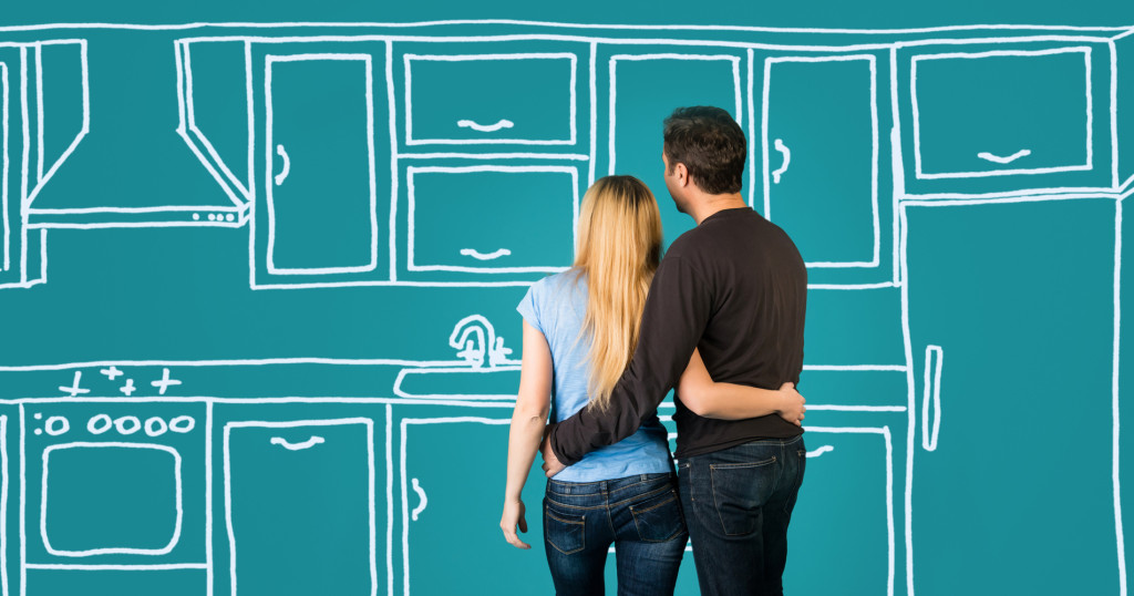 Happy embracing couple planning their home kitchen furnishing.