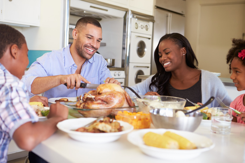 Family Sitting Around Table At Home Eating Meal