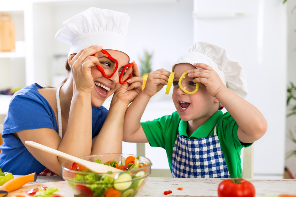 Happy family playing with vegetables in kitchen