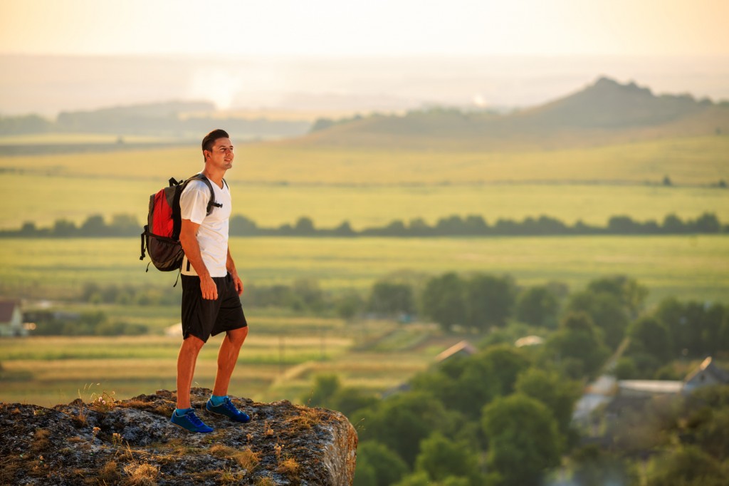 Hiker with backpack standing on top of a mountain