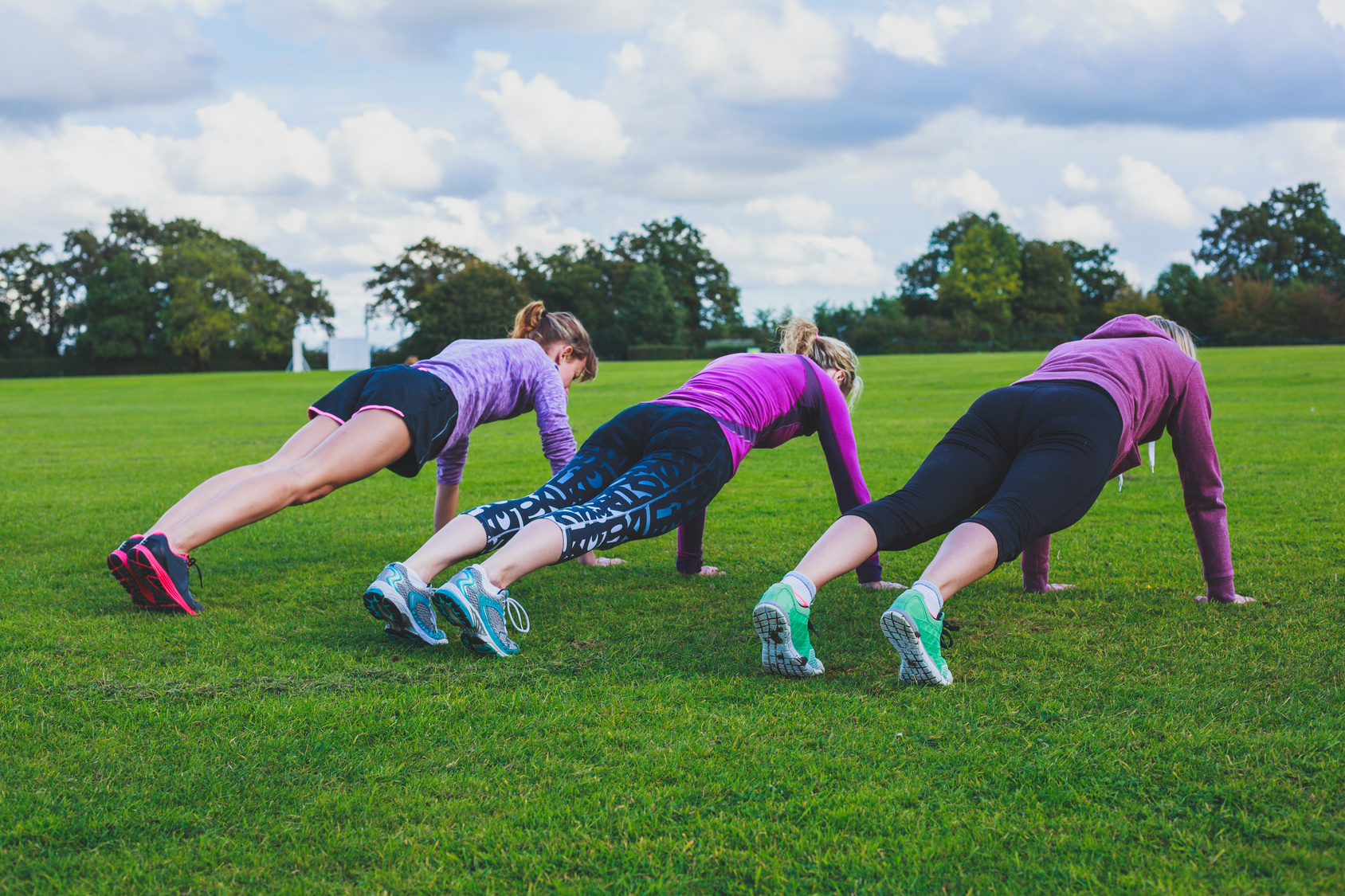 Three women doing push ups in park