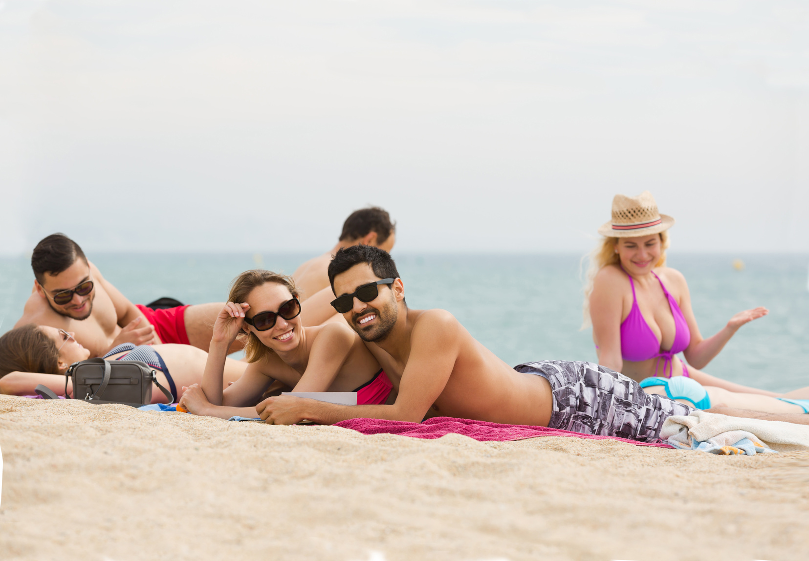 people laying on sand at beach