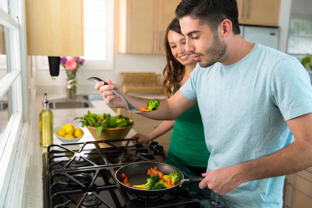 Couple cooks dinner together on stove hot food blows cool air before biting tasting