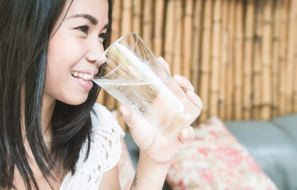 Asian woman holding a glass of water