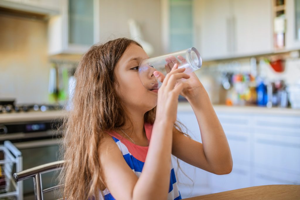 Little happy girl drinking of water