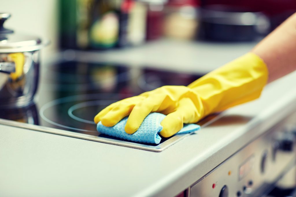 close up of woman cleaning cooker at home kitchen