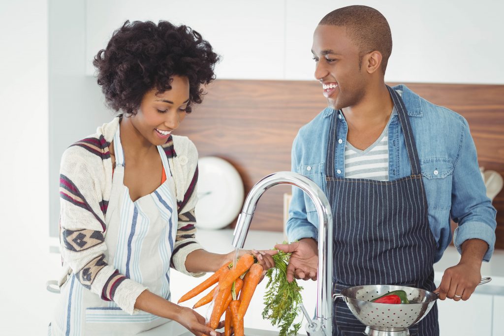 Happy couple washing vegetables