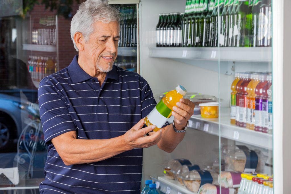 Man Reading Information On Juice Bottle