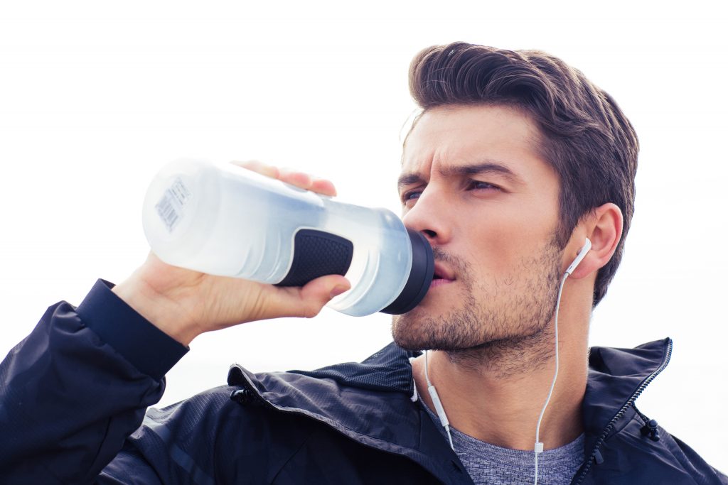 Handsome man in headphones drinking water