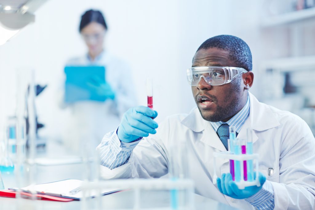 Young scientist looking at flask with hydrogen water surprisingly