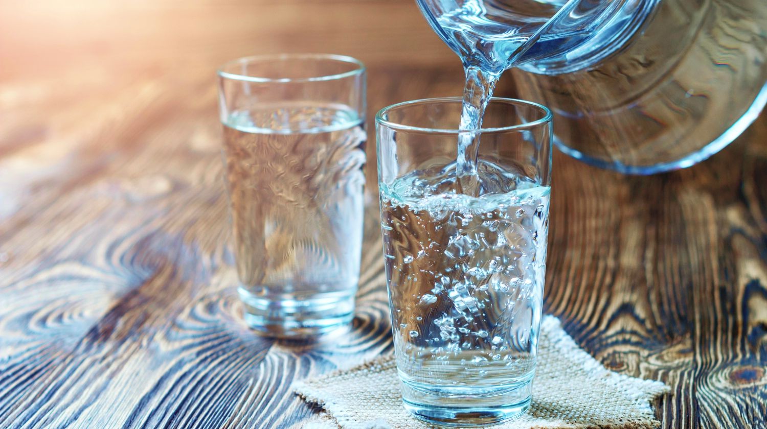 Feature | Glass of water on a wooden table. Water was poured into the beaker | Can You Drink Distilled Water | Uncovering the Truth