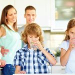 Boy and girl drinking water with lime in the kitchen | Ways To Drink More Water This Year