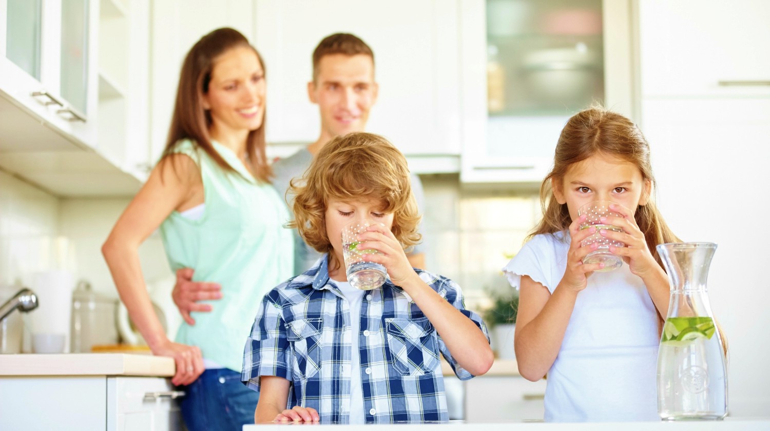 Boy and girl drinking water with lime in the kitchen | Ways To Drink More Water This Year