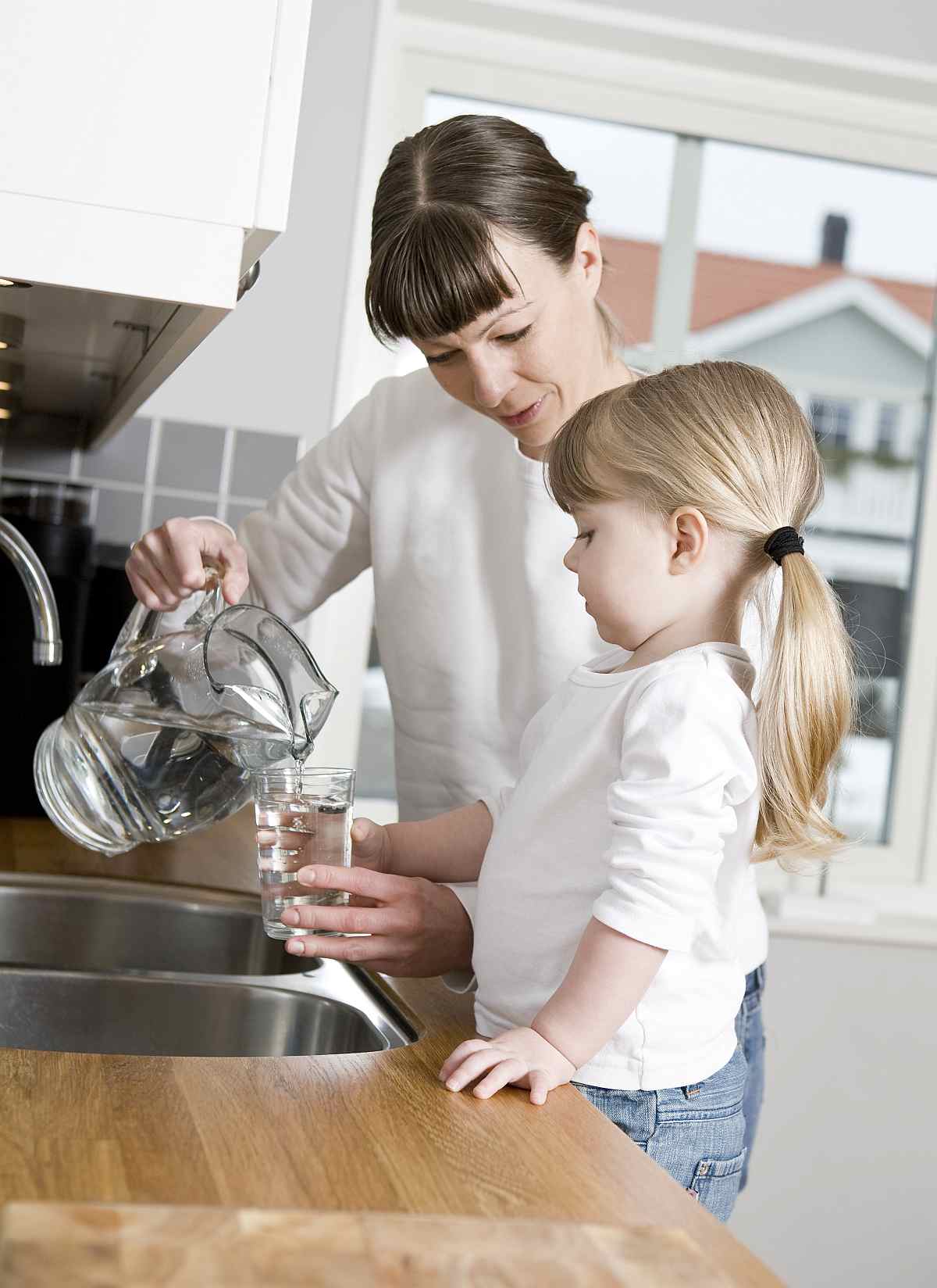 Mother pouring water on a glass with her daughter | Tyent Alkaline Water Ionizer Company Has Much to Offer You