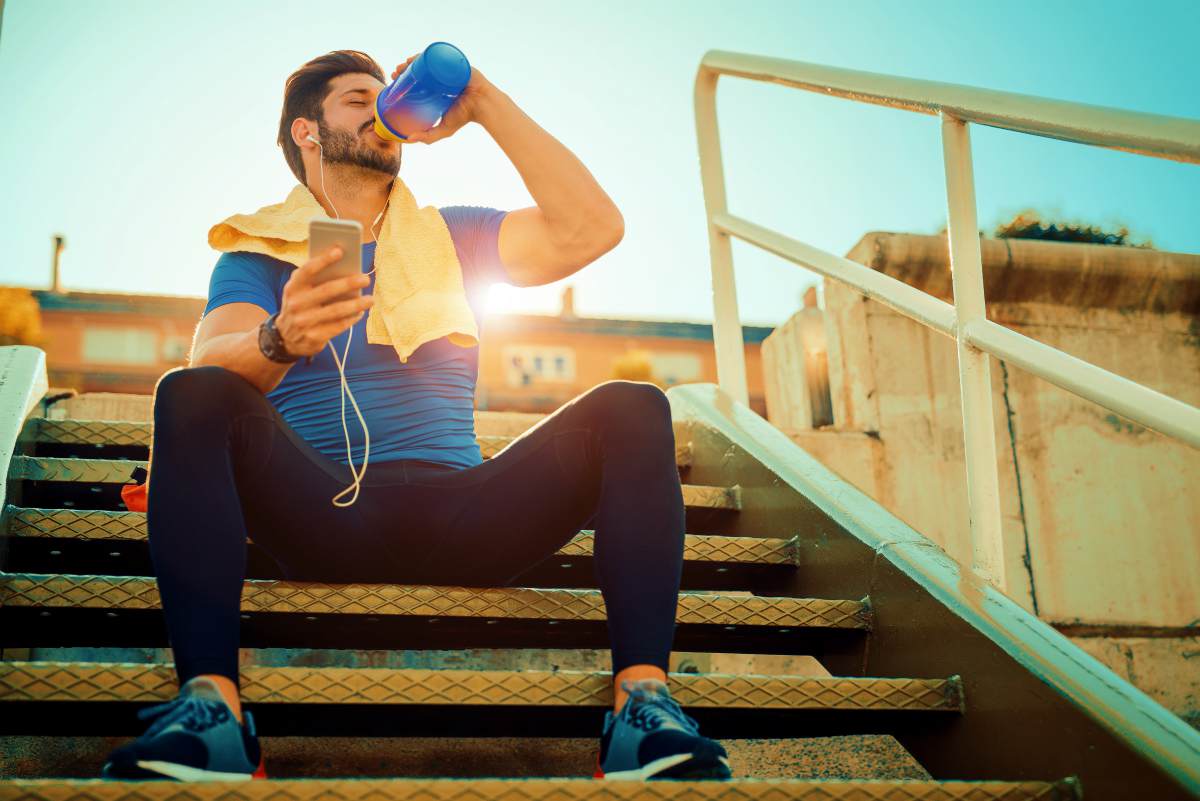 Tired fitness man sweating taking a break listening to music | Ways To Drink More Water This Year