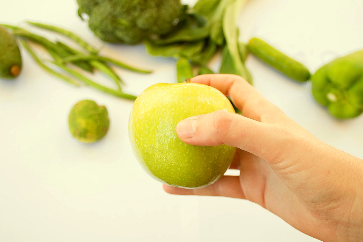 Holding apple on vegetable background | Why Should You Wash Fresh Produce with Alkaline Water?
