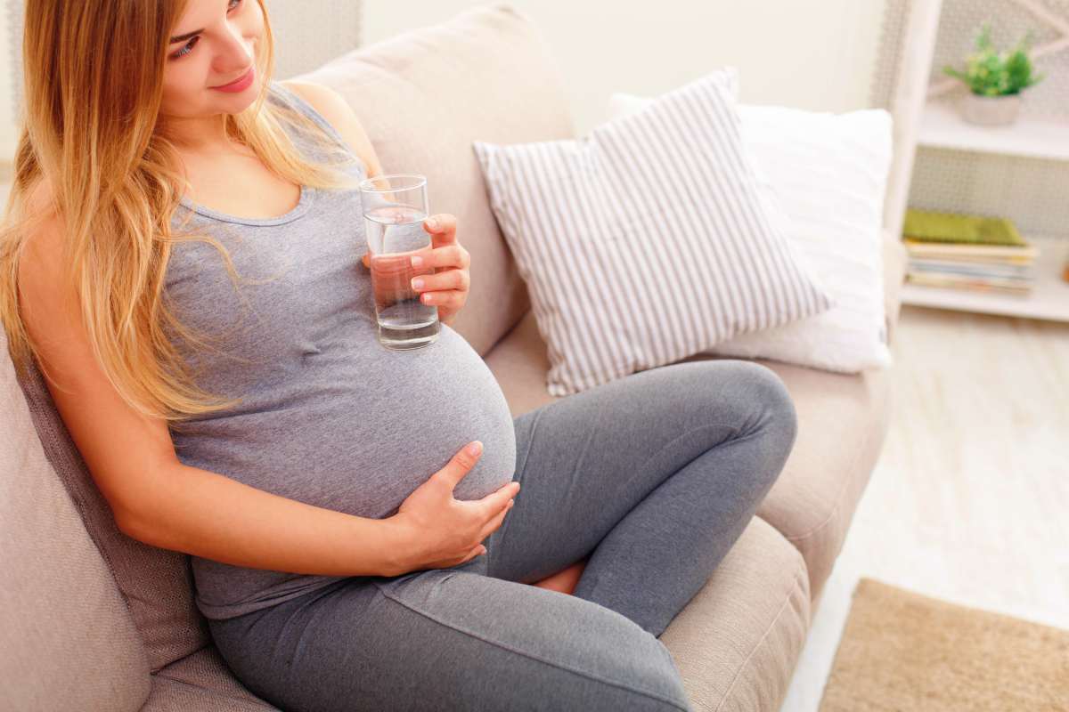 Sitting pregnant woman drinking water | Alkaline Water And Pregnancy