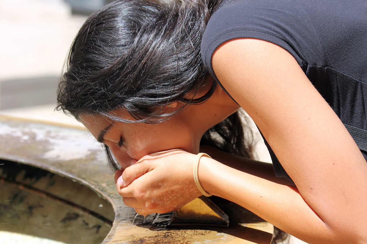 Girl with black hair drinking water | Is it Safe to Drink from a Public Water Fountain?