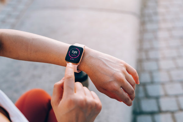 Health conscious runner woman using a smartwatch to check her vitals and distance