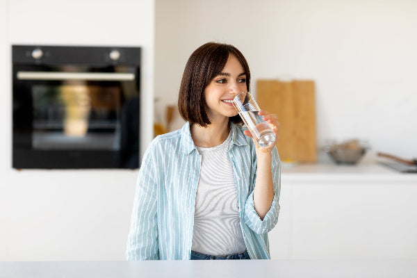 Young healthy Woman drinking water from a glass in modern a kitchen