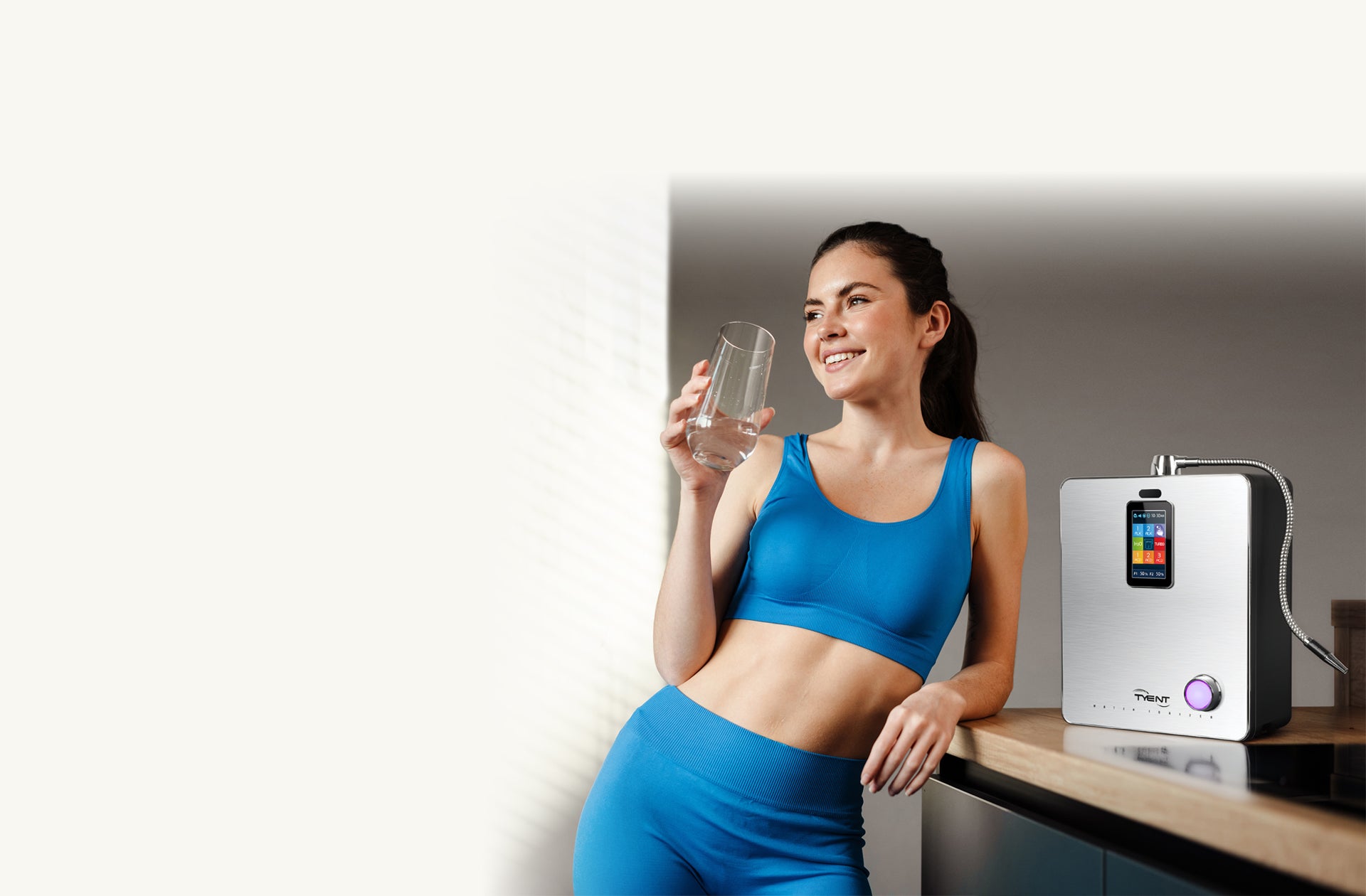 A fit young brunette woman wearing blue workout clothes drinking alkaline water