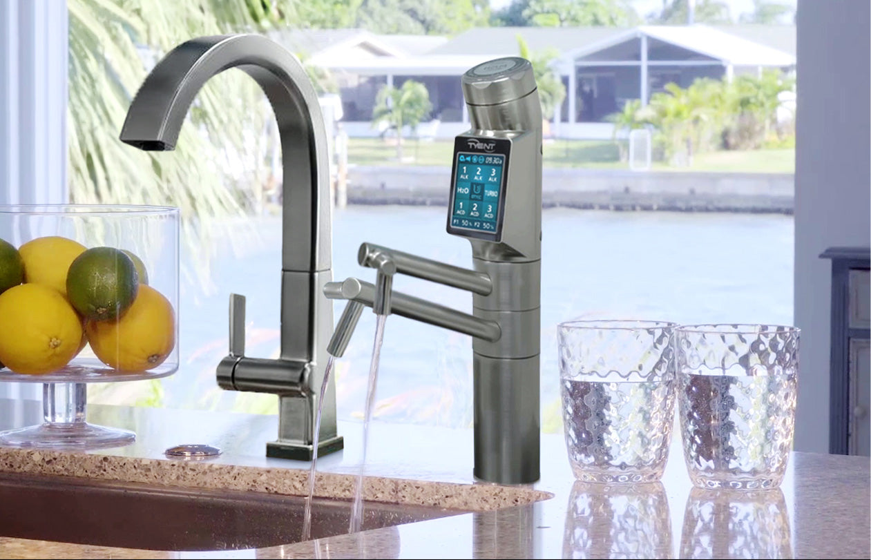 A countertop alkaline water ionizer machine sitting on a clean kitchen counter next to a glass of water, photographed in natural light.