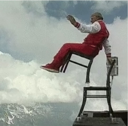Man dangerously balancing on multiple chairs